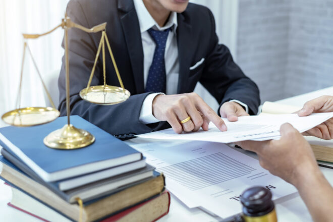 A trust litigation lawyer with a client going over a case, showing evidence of a conflict of interest, which is a violation of trustee duties in California.