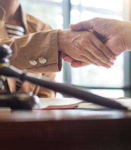 A corporate trust attorney shaking hands with a client with a gavel in the forefront of the picture.