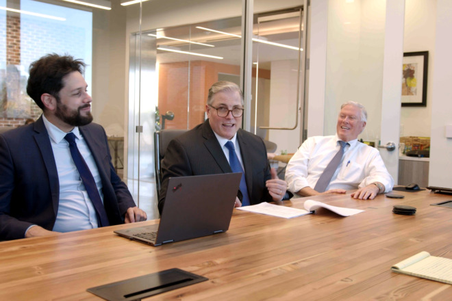 The Gokal Team smiling and talking at a conference table about a client who came and asked the question, Can a trustee live in a trust property in California?