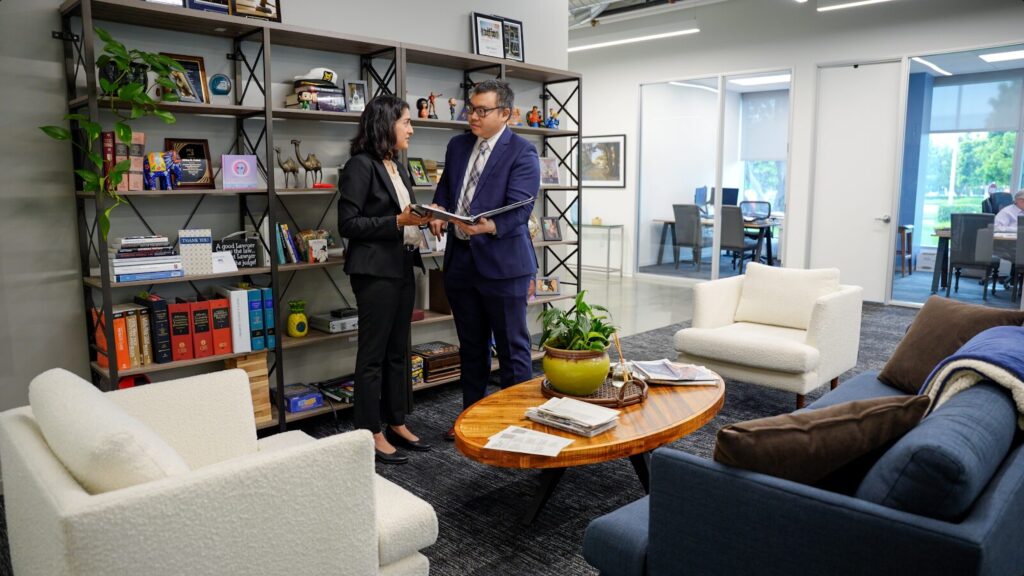 Anum and Andrew discussing a case in the Gokal Law Group office that revolves around a trustee not acting in the best interest of the beneficiaries or trust and reviewing a binder.